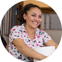 housekeeper smiling and holding cleaning supplies